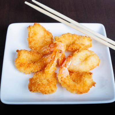 Crispy fried shrimp and chopsticks on a square white plate.
