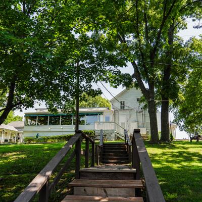 Wooden staircase leading up toward a white-sided building surrounded by trees.
