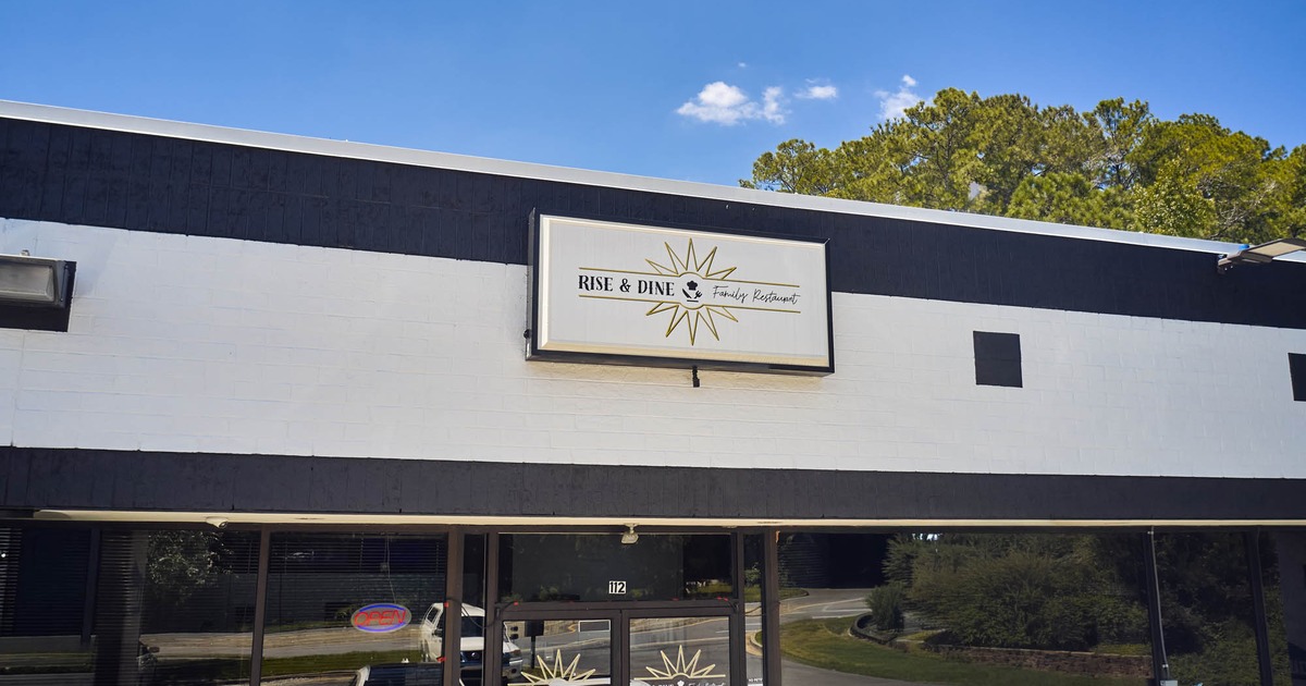 Rise and Dine restaurant exterior with signage and glass door against a blue sky