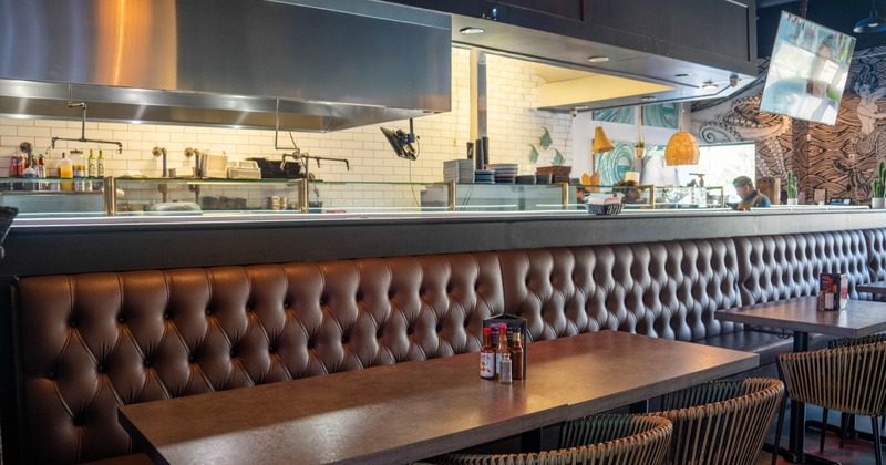 Interior of a restaurant with leather banquettes, dark wooden tables
