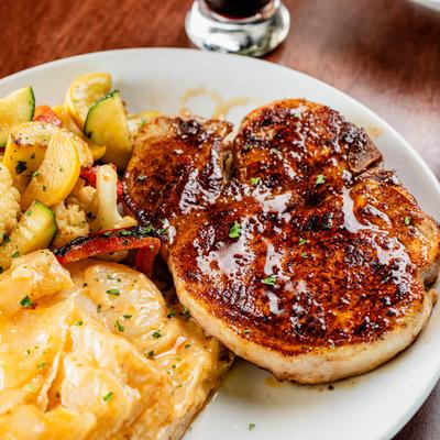 Bourbon glazed pork chop with au gratin potatoes and vegetables.