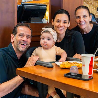 A family of four dining with a baby at restaurant table.