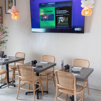 Dining area with woven chairs and an overhead TV.