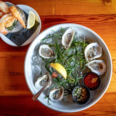 Oysters on the half shell and shrimp with two sauces and lemon wedges.