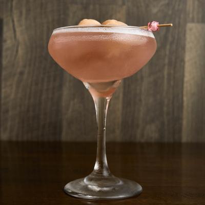 A vibrant pink cocktail in a glass, placed on a table.