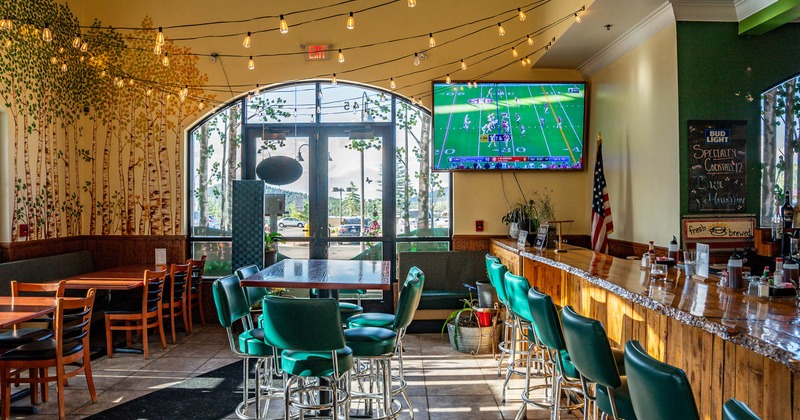 Interior, tables and chairs, bar on the right, big TV screen on the wall