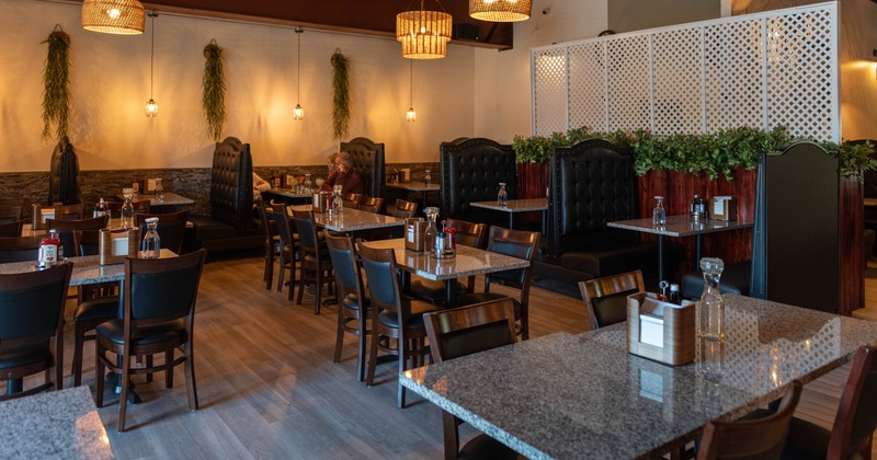Restaurant interior with granite tables, wooden chairs, and tufted black booths