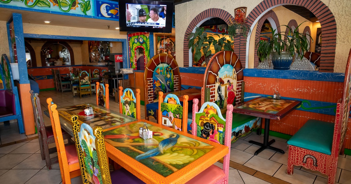 Interior of a colorful Mexican restaurant with vibrantly painted tables and chairs