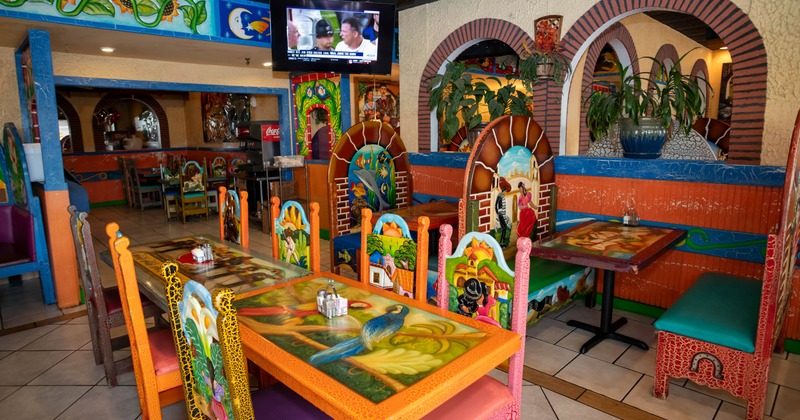 Interior of a colorful Mexican restaurant with vibrantly painted tables and chairs