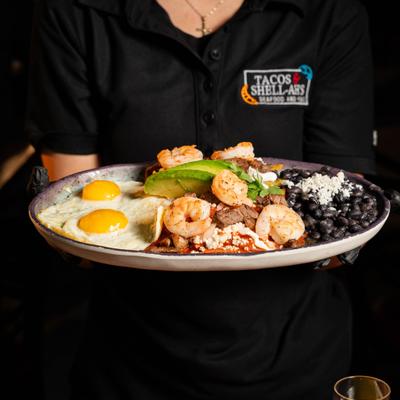 Breakfast platter with fried eggs, shrimp, black beans, and avocado.