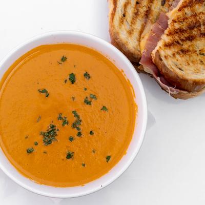 Creamy Tomato Bisque served with a grilled cheese sandwich.