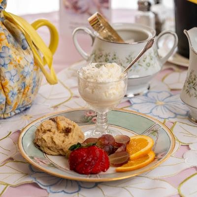 Scone and Devon Shire Cream on a table with tea set.