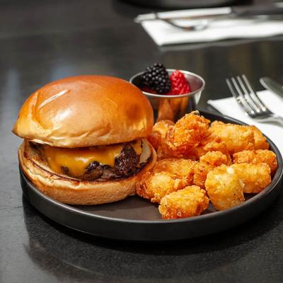 Cheese burger served with tater tots and fresh berries.