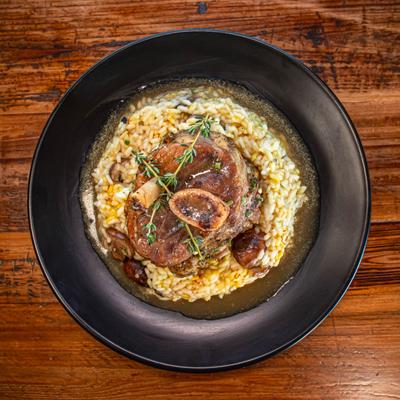Osso buco served over risotto in a black bowl
