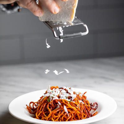 Grating cheese over a plate with spaghetti Bolognese