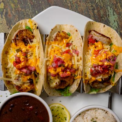 Portion of shrimp tacos served with black beans and rice.