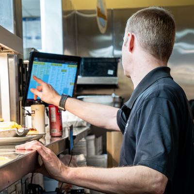 A kitchen employee utilizing a touch-screen monitor.