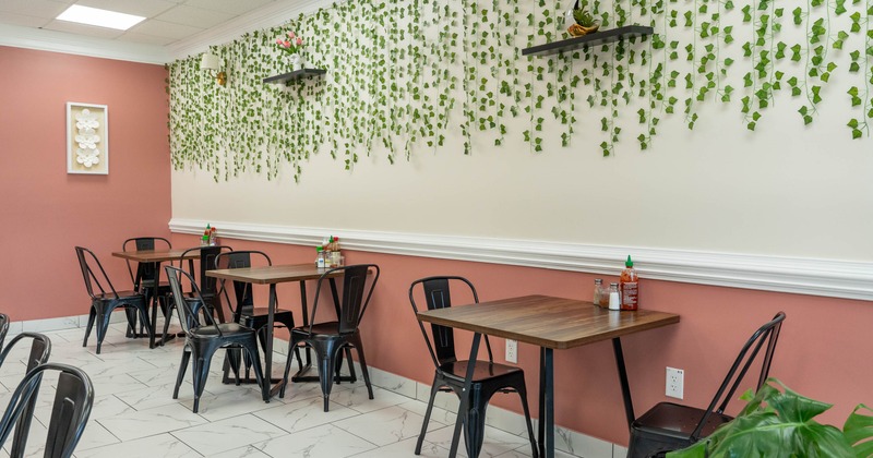 Interior - green vine decorations, cream walls, coral pink accents, wooden tables, metal chairs
