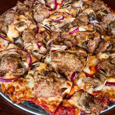 The Classic Pizza tipped with sausage, mushrooms, and red onions, close-up.