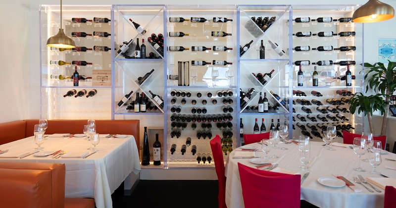 Nicely done interior dining area with set tables, wall wine racks