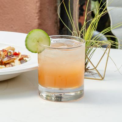 Peach cocktail garnished with a cucumber slice