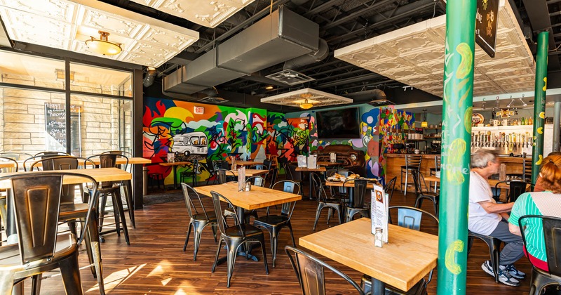 Interior, tables and seats in the dining area, a bar, mural art