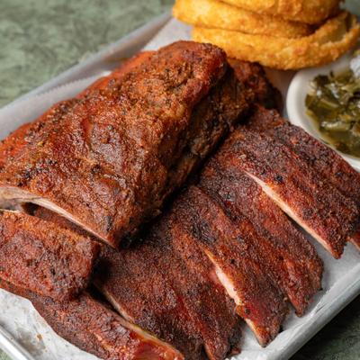 Full rack of ribs served with collard greens and onion rings.