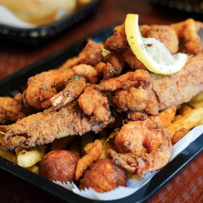 Fried seafood platter with fish, shrimp, hash puppies. and fries.