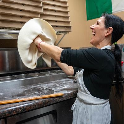 Pizza maker spreading dough.