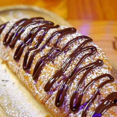 Croissant topped with powdered sugar and chocolate drizzle.