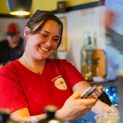 A friendly bar employee pours soda from a bar gun into a glass.