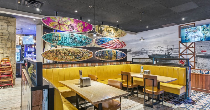 Restaurant interior with yellow booth seating and surfboard-themed decor