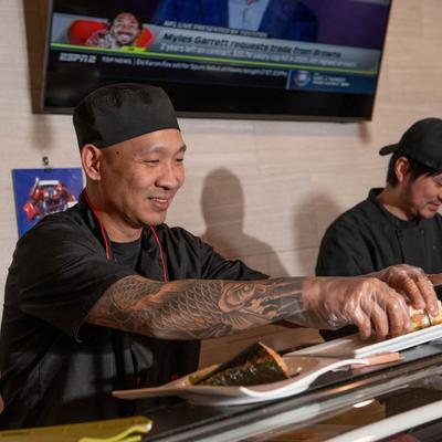Sushi chef preparing sushi rolls.