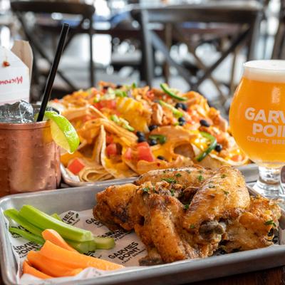 Chicken wings with celery and carrots served with drinks and loaded nachos.