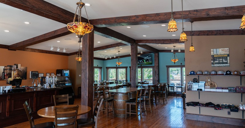 Rustic interior with wooden beams, Tiffany lights, tables, and a bar area.