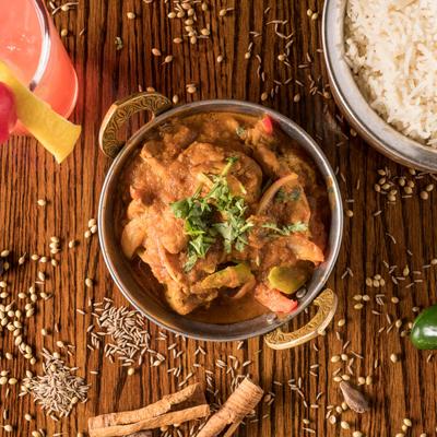 Bowl of spiced chicken in thick gravy, served with rice.
