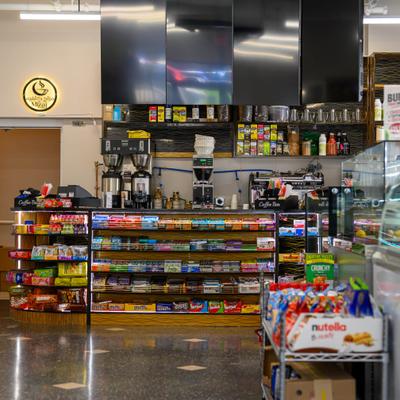 Convenience store counter featuring shelves stocked with various snacks and drinks.