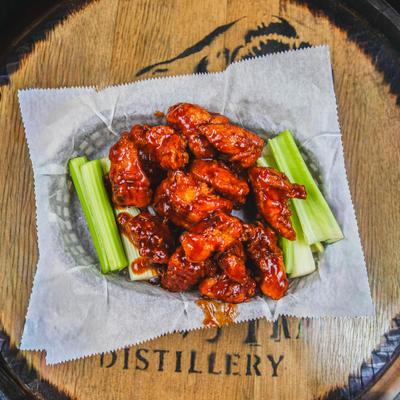 BBQ wings served in a basket lined with paper with a side of celery sticks.