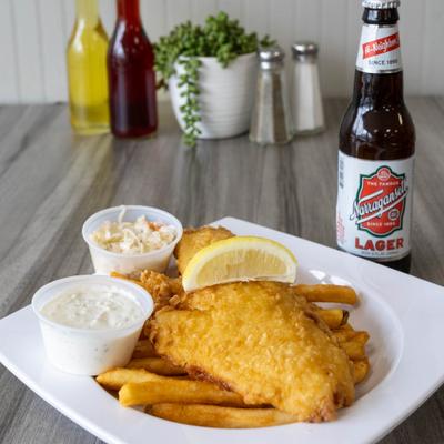 Fish and chips plate with fries, coleslaw, tartar sauce, and lemon wedge.
