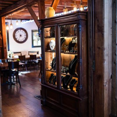 Dark wood antique-style cabinet with glass doors showcasing high-end merchandise.