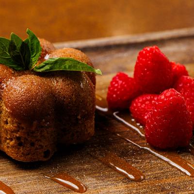 Mini Bundt cake on a wooden board with raspberries and caramel sauce.
