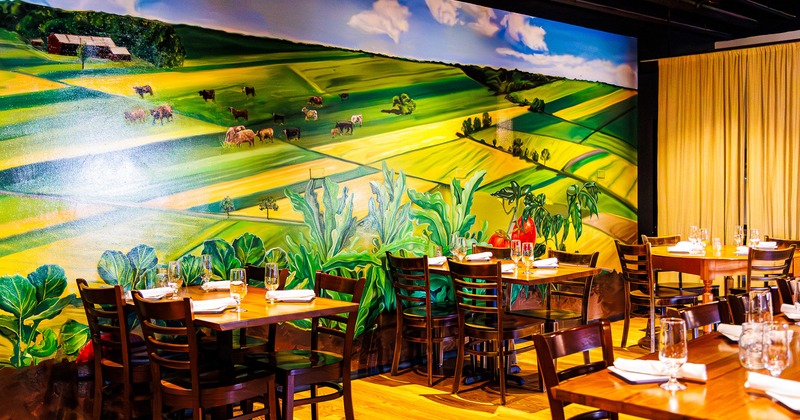 Restaurant interior, dining area with set tables, a large mural on the wall