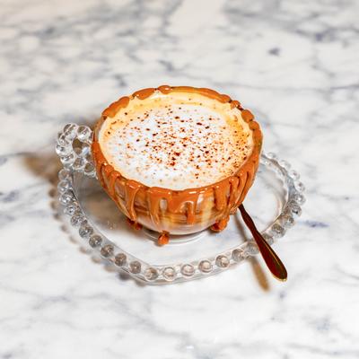 Cappuccino served in a glass cup on a glass saucer.