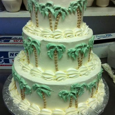 Three tier cake with palm tree decorations.