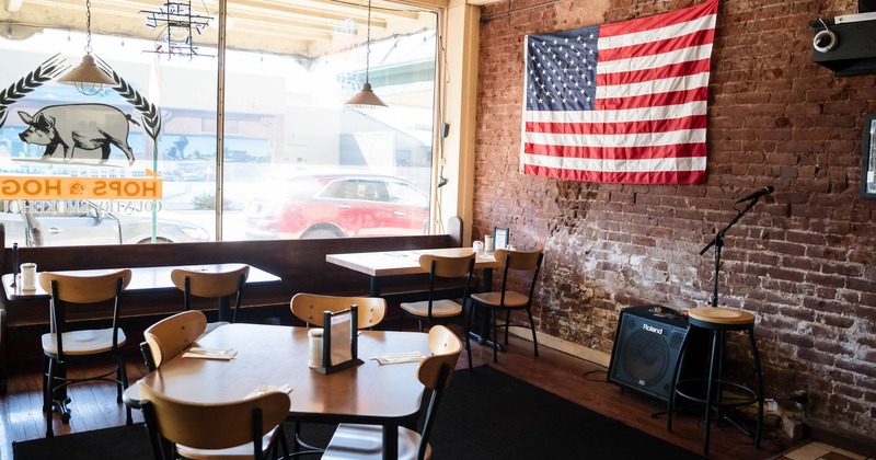 Interior seating area with tables, chairs and an American flag on a brick wall