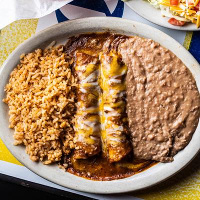 A plate with two enchiladas  smothered in sauce, served with rice and beans.