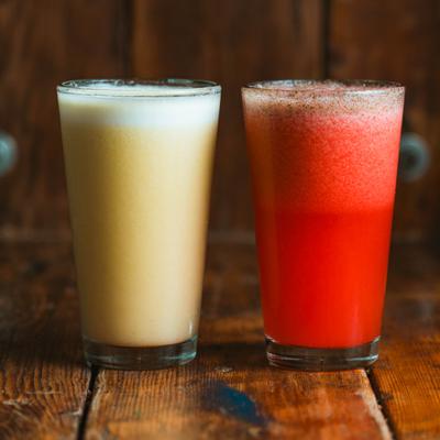 Two fruit juices served in tall glasses.