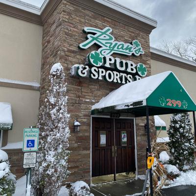 Ryan's Pub & Sports Bar exterior entrance with snow-covered trees and a green awning.