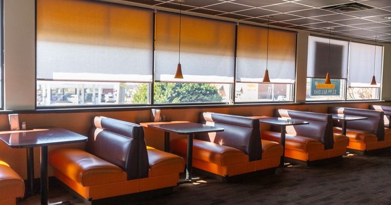 Interior, lined up bench seating with tables by the widow