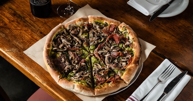 Pizza with pesto, prosciutto, mushrooms, and parmesan